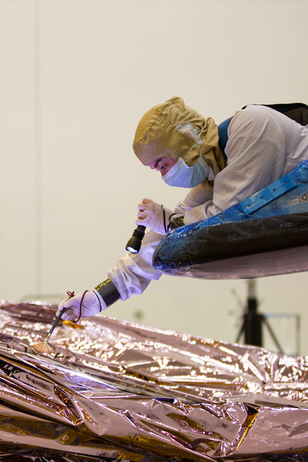 A Northrop Grumman engineer is suspended above the James Webb Space Telescope Sunshield.