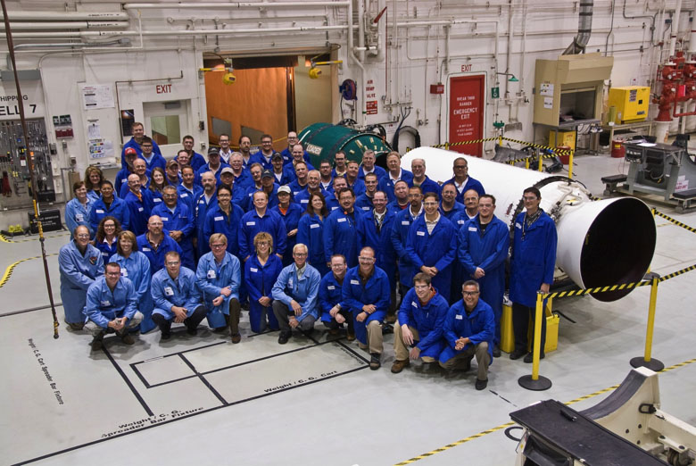 people in front of rocket motor in manufacturing facility