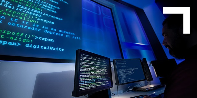 man looking at large computer screen with code
