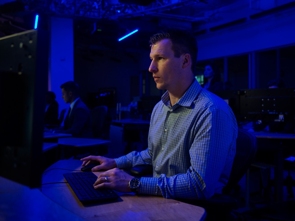 man sitting at computer desk in darkend room