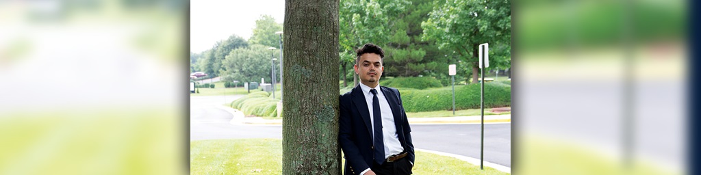 man in suit leaning against a tree