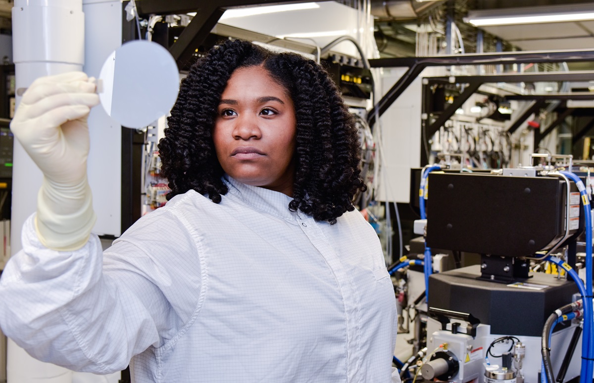 Young Black woman in lab attire examine an object in a lab