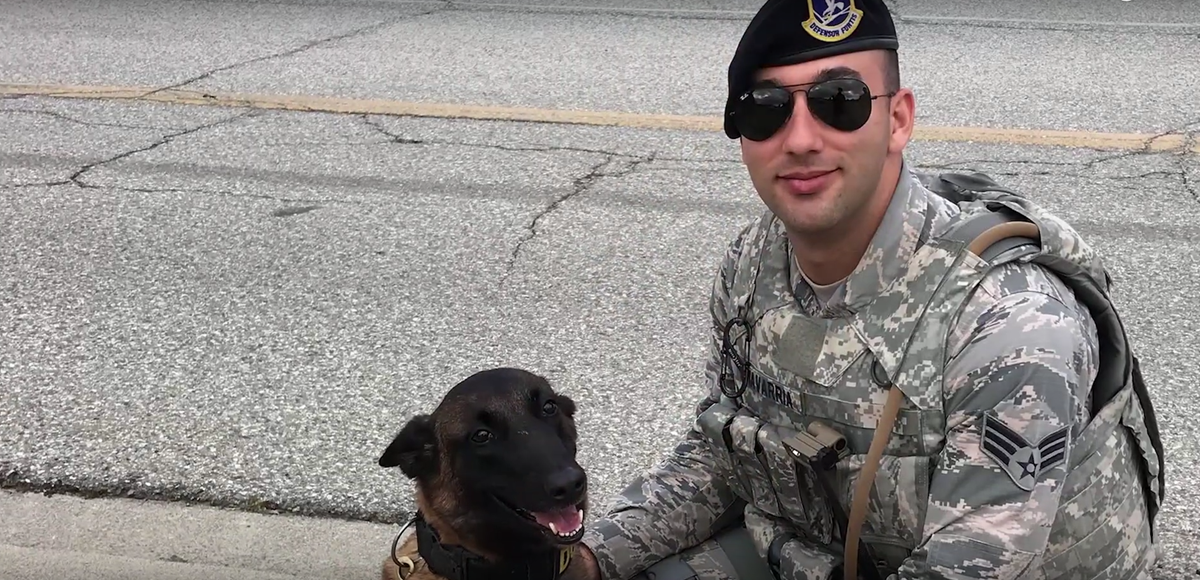 White male veteran in uniform poses outside next to dog