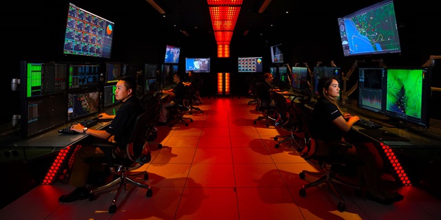 men and women on computers in large room