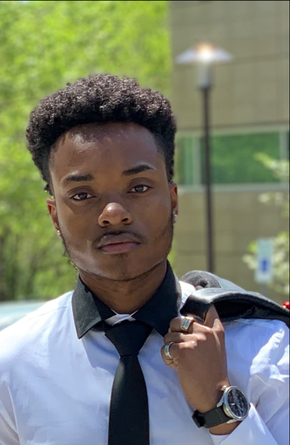 Young Black man poses in business attire outside