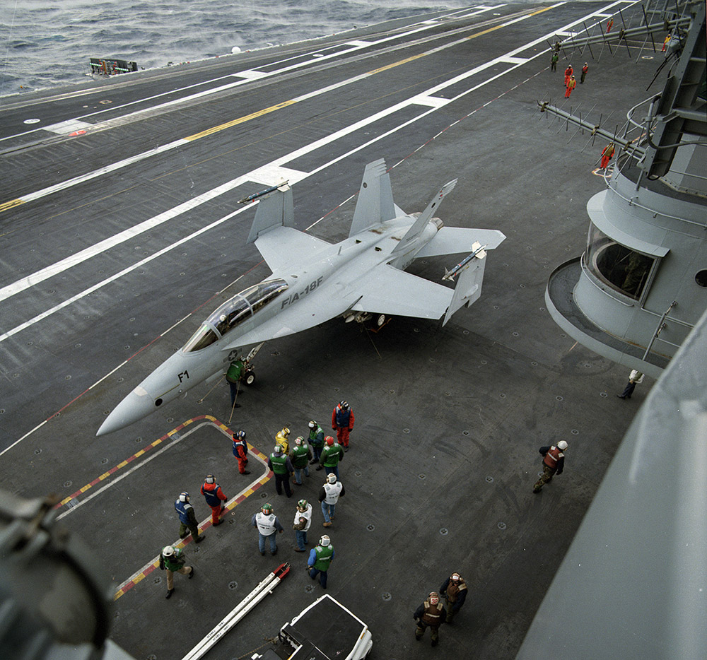 FA-18 stationed aircraft carrier deck with several personell around it