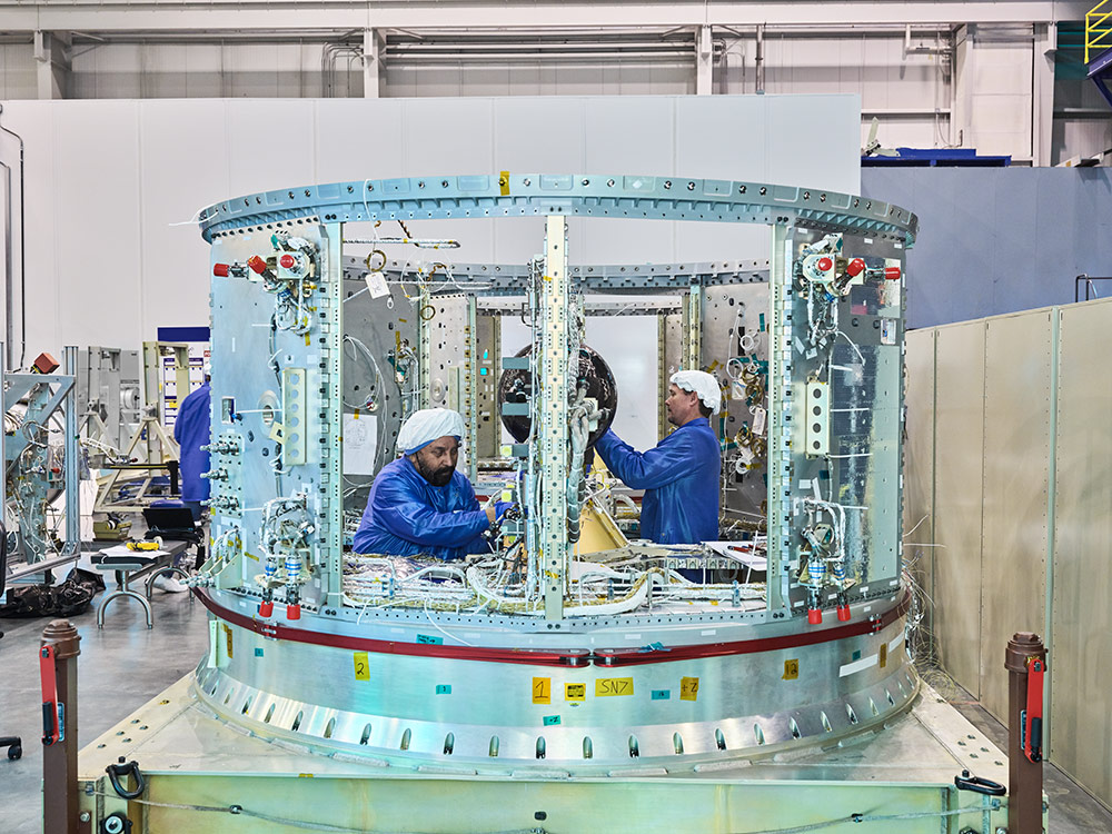 Two engineers work inside a large machine in a lab