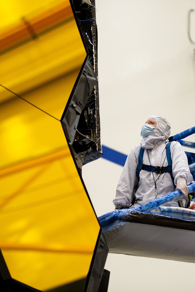 White female technician completes an operation on a space telescope