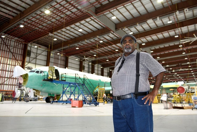 man standing in front of an airplane inside of an airplane hangar