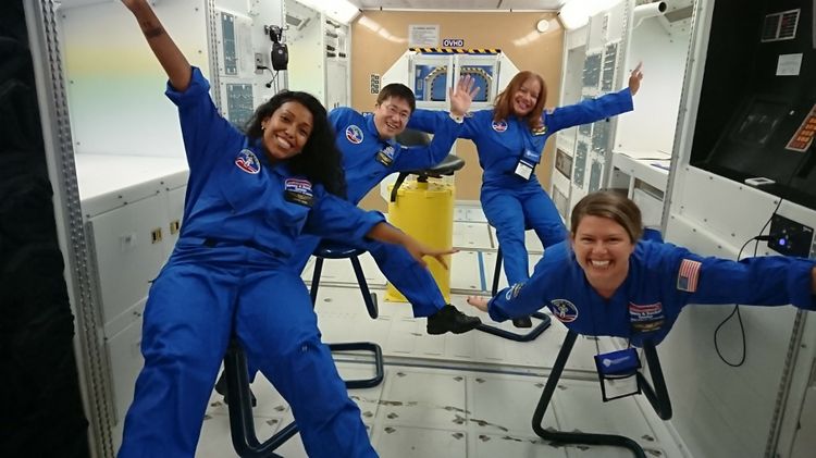Young students in space suits smile floating in zero gravity