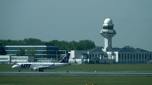 A plane grounded in front of air traffic control tower at Warsaw Chopin International Airport