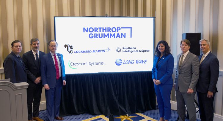four people standing in front of a sign with Northrop Grumman logo