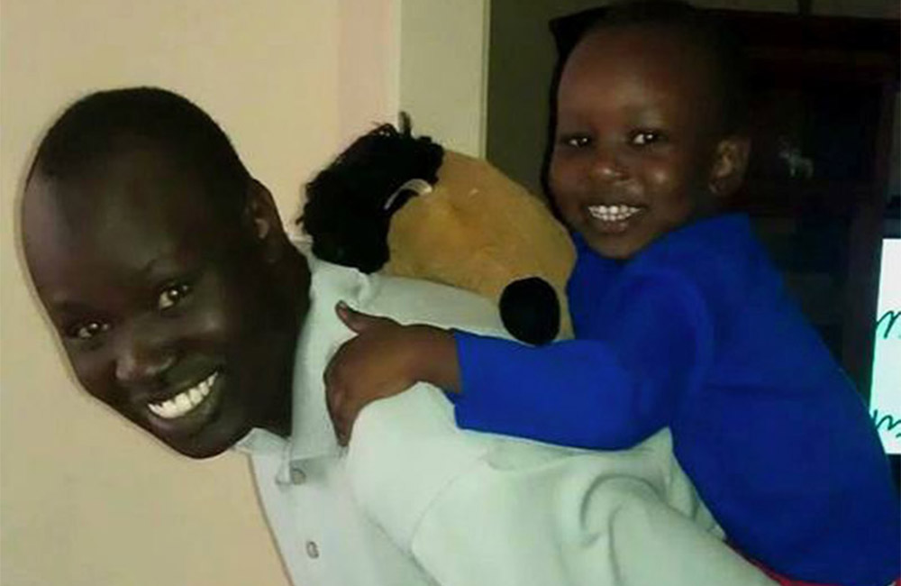 Black male smiling while carrying male child on his back
