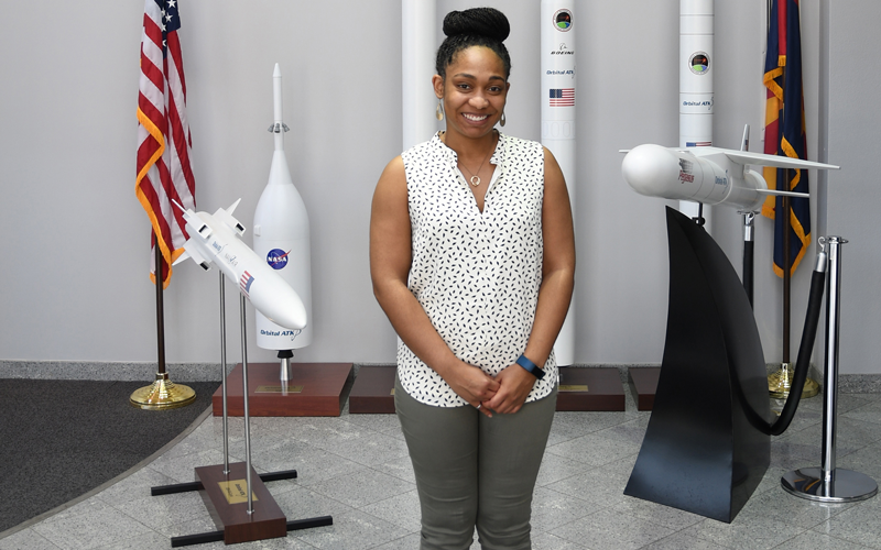 Young African American woman smiling and posing in front of model rockets