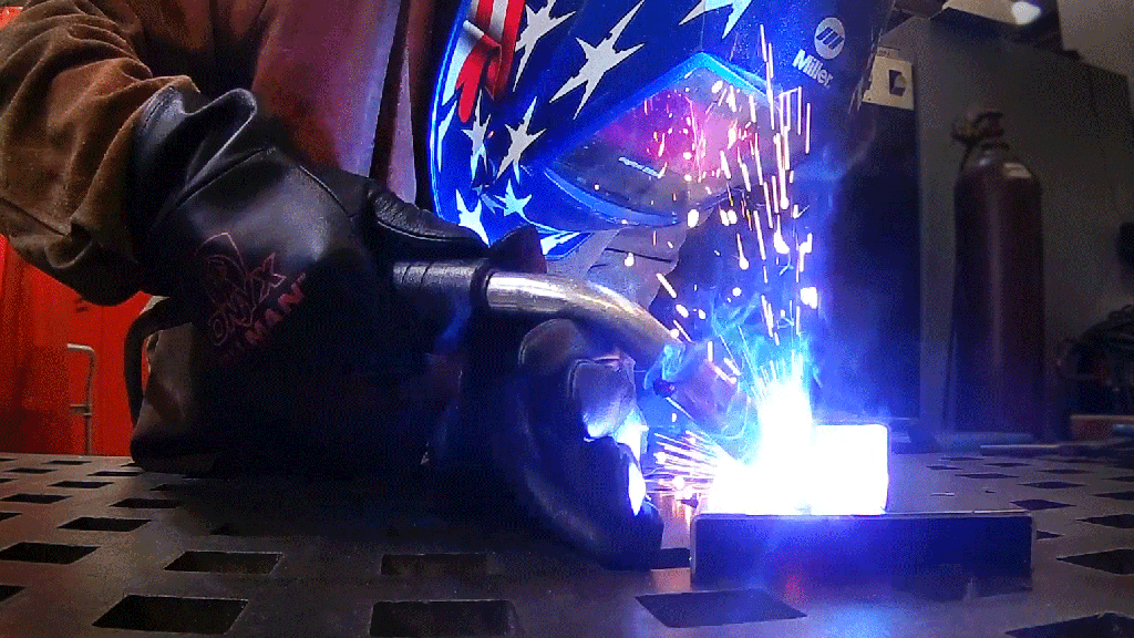 a metalworker welding and wearing a mask and gloves