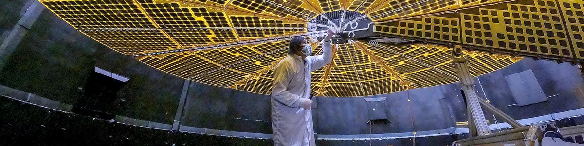 person in bunny suit inspects NASA solar arrays