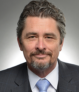 Headshot of white man with mustache and goatee in a suit.