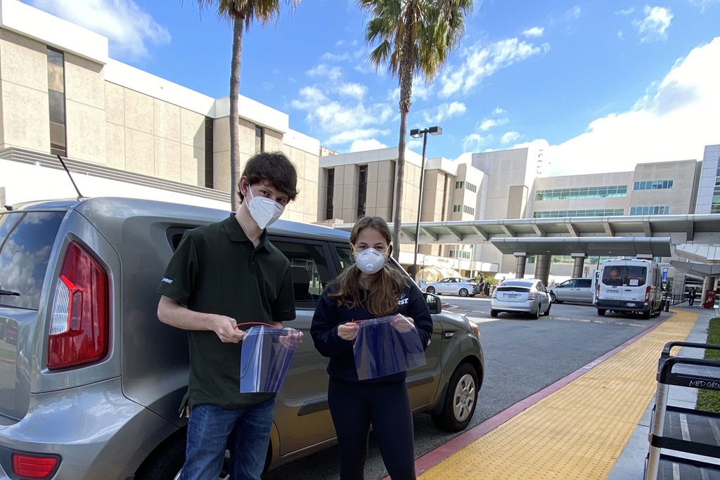 white male and female wearing protective masks in front of van