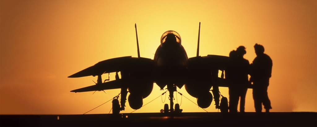 A silhouette of people next to an F14 jet