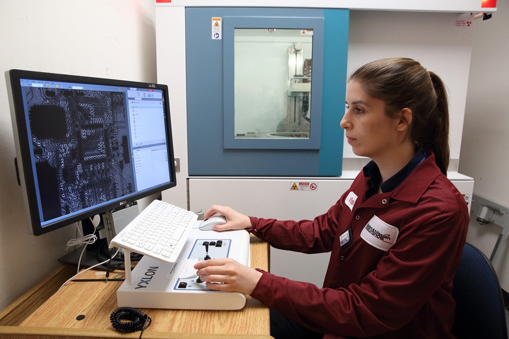a woman in a maroon lab coat works on a computer