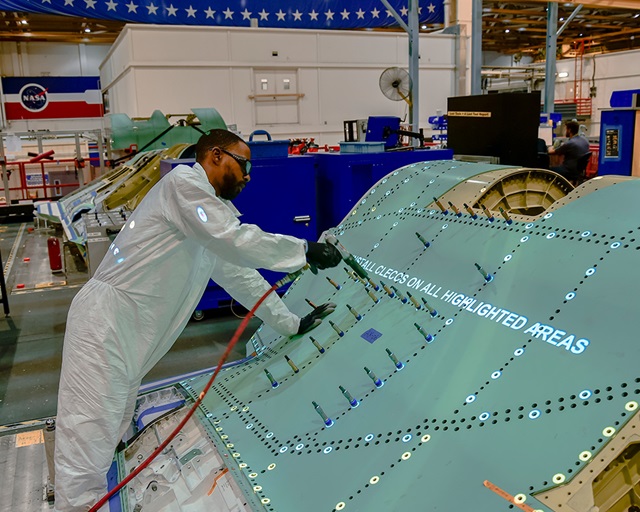 man working on military aircraft in manufacturing facility