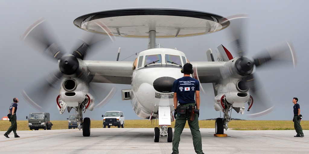 man standing in front of military plane with large propellers