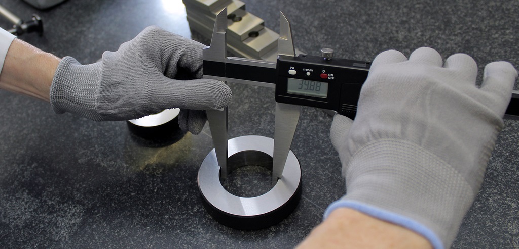 Hands operating measuring tools in a manufacturing environment.